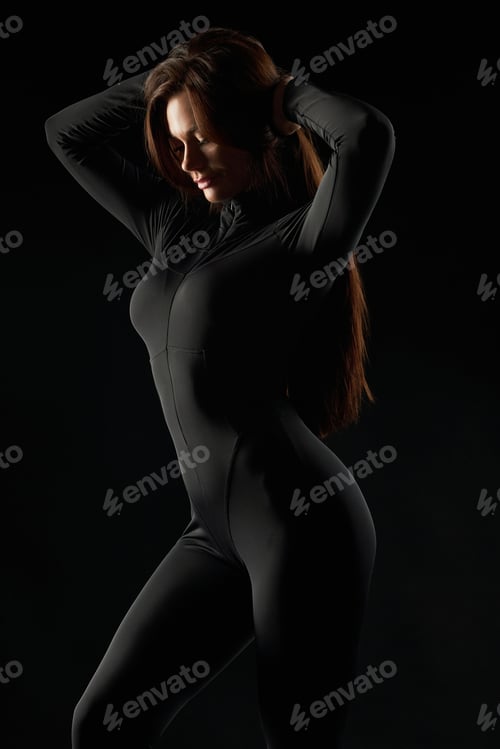 Preview: Slim, sporty female wearing bodysuit, posing in shadow.