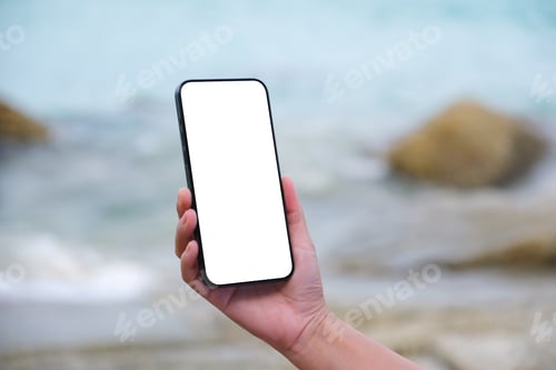 Preview: Mockup image of a woman holding mobile phone with blank desktop screen by the sea