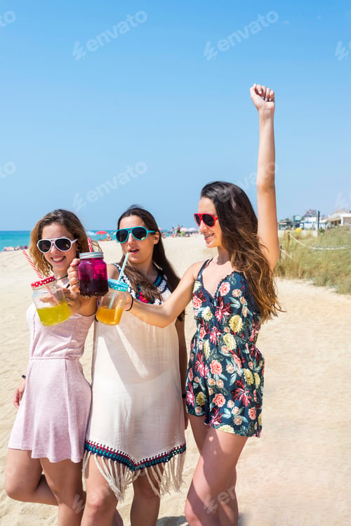 Preview: group of happy young women or female friends toasting non alcoholic drinks on summer beach