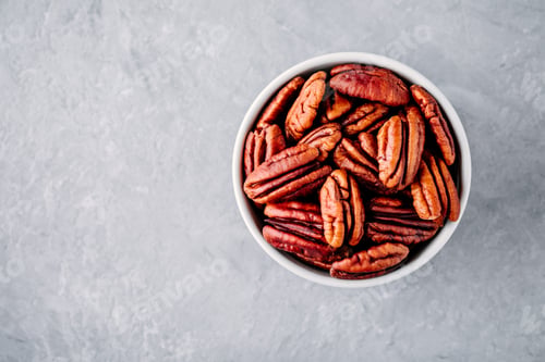 Preview: Raw pecan nuts in bowl on gray background.
