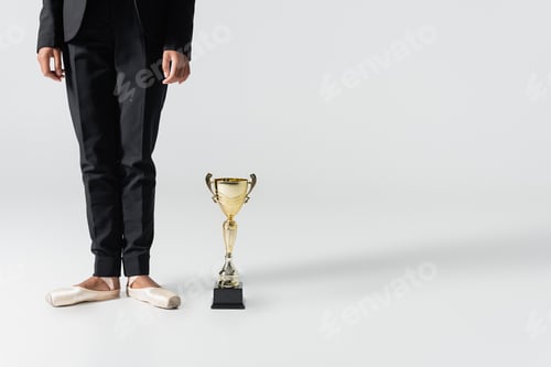Preview: cropped view of african american businesswoman in pointe shoes with golden cup on grey