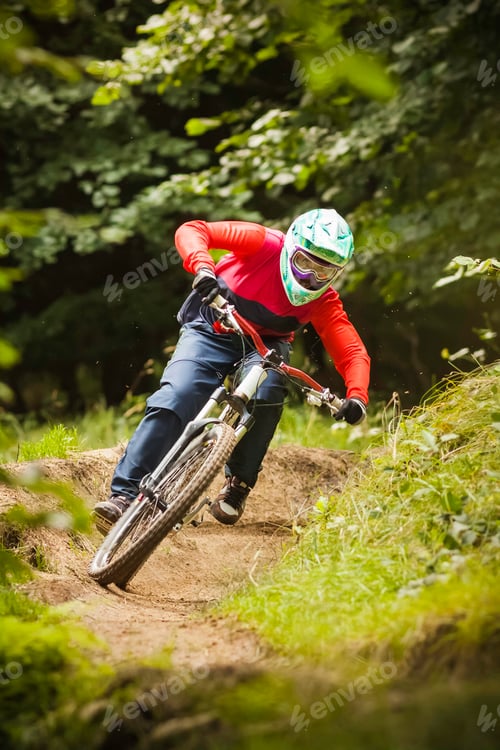 Preview: Young woman downhill mountain biking in forest