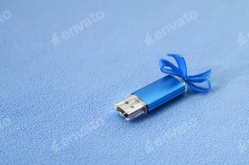 Preview: Brilliant blue usb flash memory card with a blue bow lies on a blanket