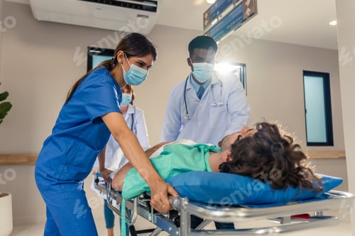 Preview: Group of diverse doctors moving seriously injured patient in hospital.