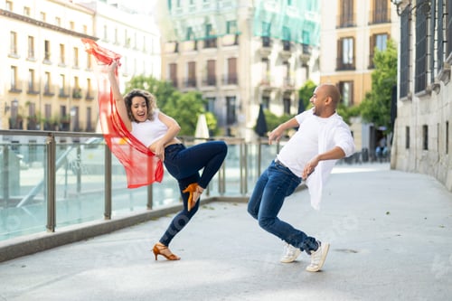 Preview: Joyful couple dances energetically with a red scarf on a sunny city street.