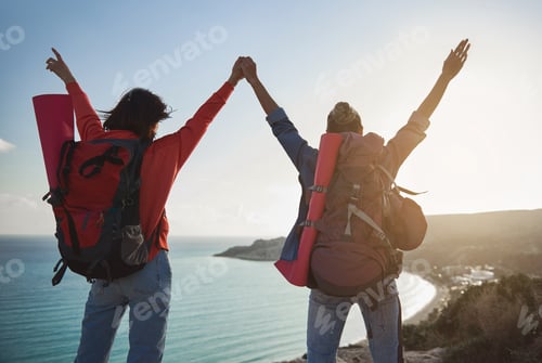 Preview: Two Girls With Rucksacks On Their Backs Standing On Hill With Hands Up. They Looking At Nature By