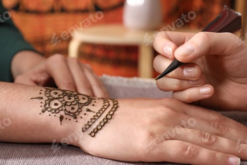 Preview: Master making henna tattoo on hand, closeup. Traditional mehndi