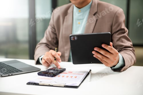Preview: Man counting coins on calculator taking from the piggy bank. hand holding pen working