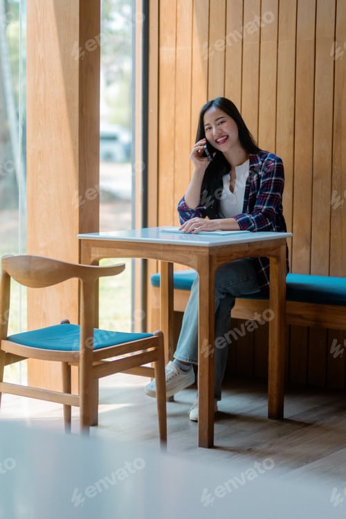 Preview: Young student talking on the phone while studying in a coffee shop