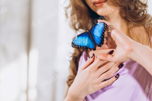Preview: beautiful sexy female model in lilac delicate dress with Morpho Nymphalidae butterfly sit on bed in