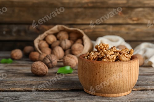 Preview: Bowl with tasty walnuts on wooden table. Space for text