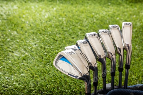Preview: Golf sticks on green grass golf course, close up view.