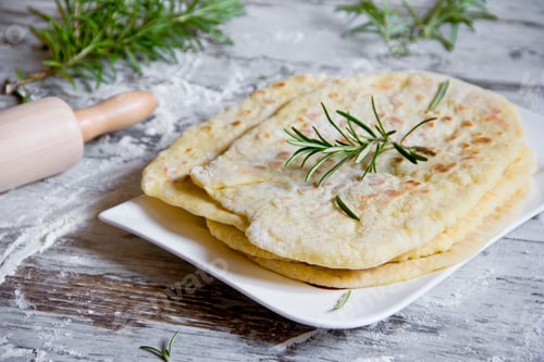 Preview: Stack of naan breads with rosemary twig on plate