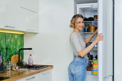 Preview: Happy woman takes out the fridge breakfast products