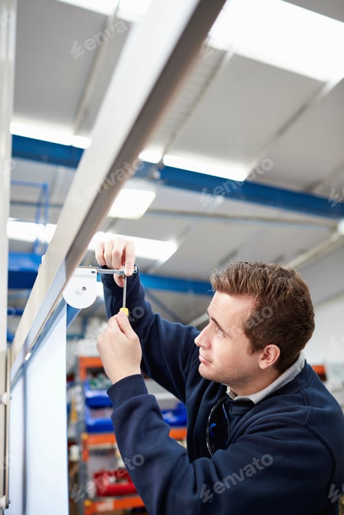 Preview: Male worker measuring roller blind in factory
