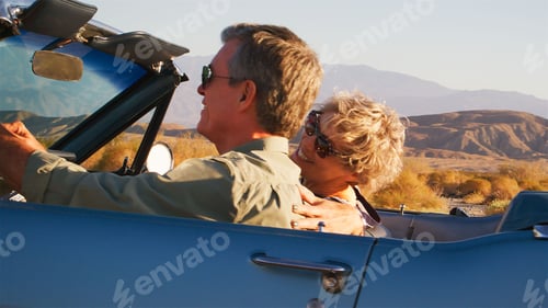 Preview: Side View Of Senior Couple On Road Trip Driving In Classic Convertible Car Along Country Road