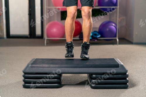 Preview: close-up of the legs of a guy athlete works out in a fitness hall jumps on a sports bridge