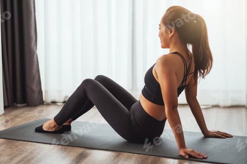 Preview: Asian woman sitting on training mat and do stretching to warm up before workout at home