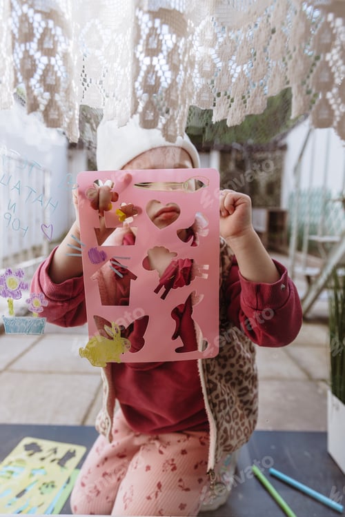 Preview: Portrait of a little girl drawing pictures on a window glass.