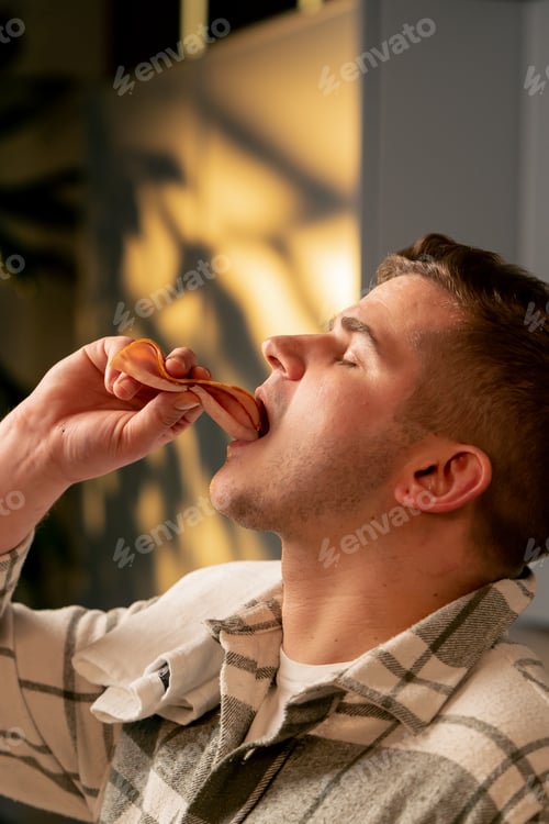 Preview: close-up of young guy in love guy in a beautiful kitchen eating shredder background sunset sun on