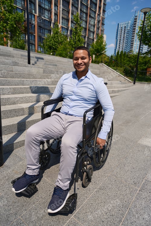 Preview: Cheerful wheelchair-bound male person posing for camera outdoors