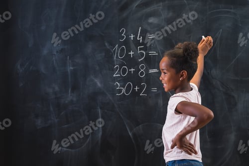 Preview: Mixed race elementary school girl solving math problems on chalkboard