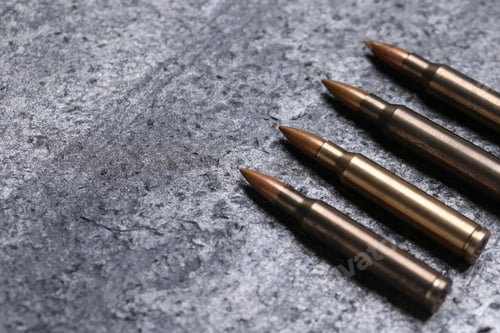 Preview: Firearm cartridges on grey table, closeup. Space for text