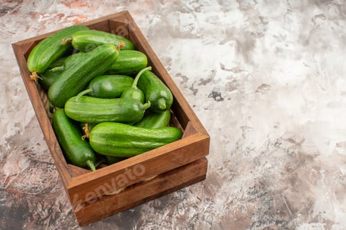 Preview: Front view of a brown wooden basket with full of organic natural fresh cucumbers