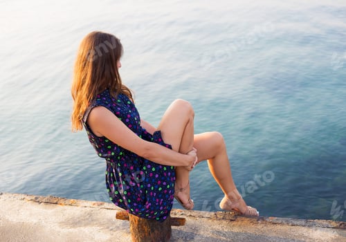 Preview: The girl in a beautiful dress is sitting on the pier.