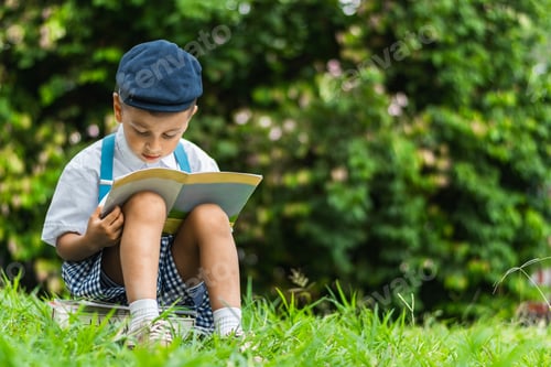 Preview: little Latino boy sitting in the park reading a book, very concentrated, looking at