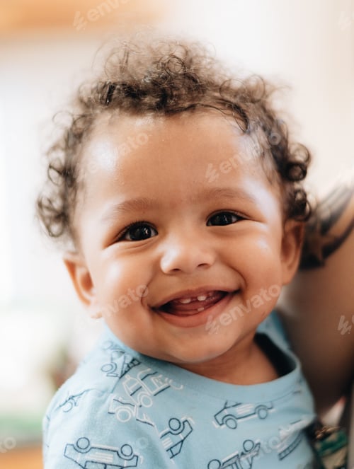 Preview: Happy diverse baby boy with curly hair laughing, smiling at the camera
