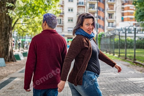 Preview: Back view of two friends walking in the park. She turns around to look at the camera.