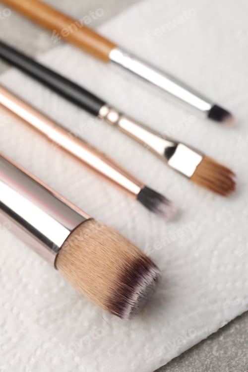Preview: Clean makeup brushes with napkin on table, closeup