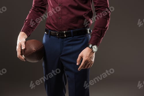 Preview: cropped shot of man holding rugby ball isolated on black