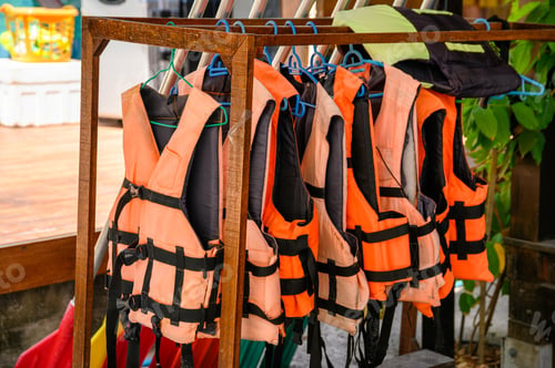 Life Vests Hanging on Rack Near Water
