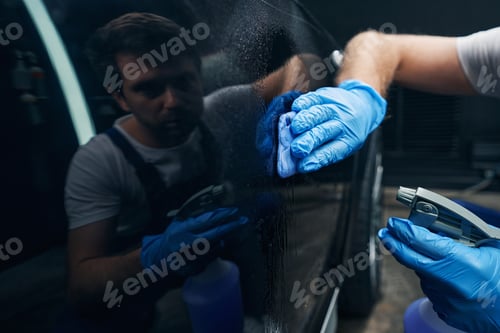 Preview: Auto mechanic wiping car surface with cleaning rag