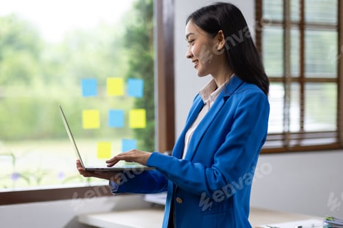 Preview: Happy excited Asian woman holding a laptop smartphone and winning the prize.
