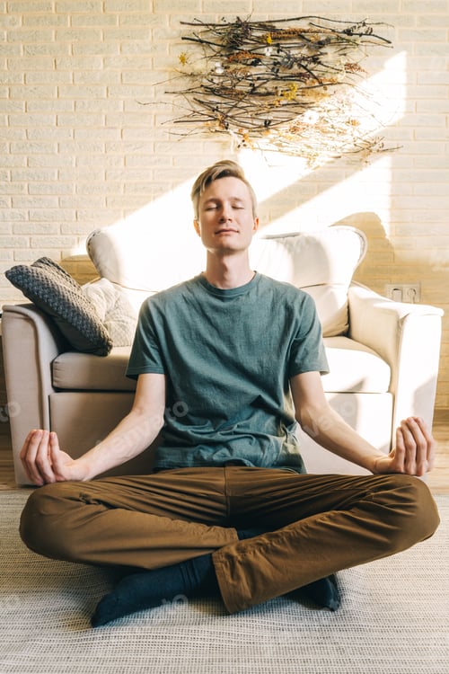 Preview: Young Man Meditating Indoors Sitting on Floor