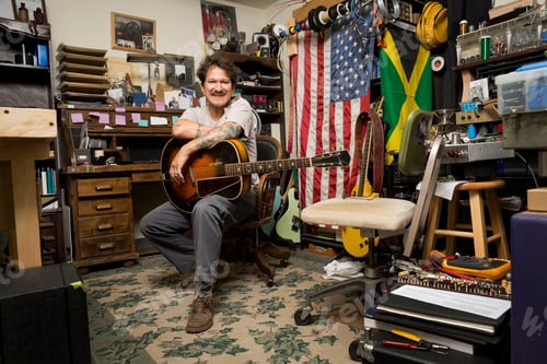 Preview: Man holding guitar looking at camera smiling