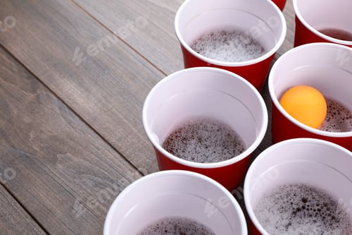 Preview: Plastic cups and ball on wooden table, space for text. Beer pong game