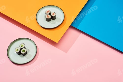 Preview: fresh maki with salmon and cucumber on blue, pink, orange surface