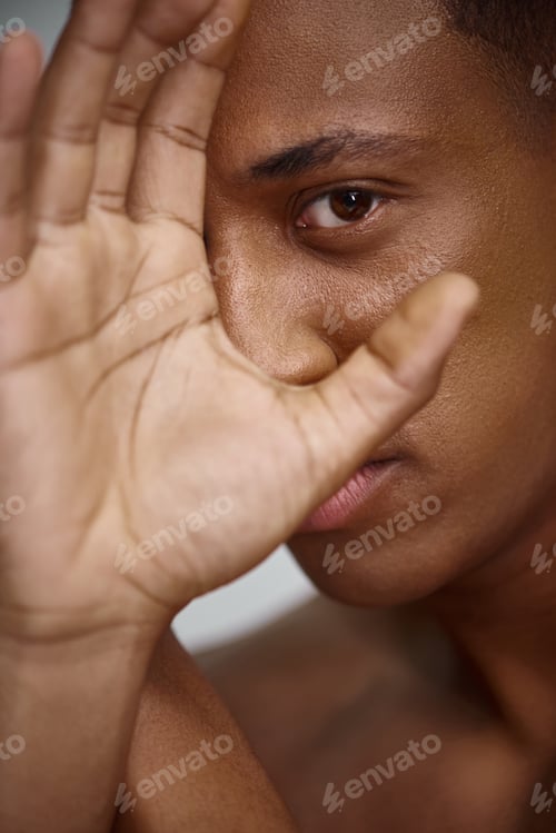 Preview: close up of handsome appealing african american man with hand in front of face, fashion concept