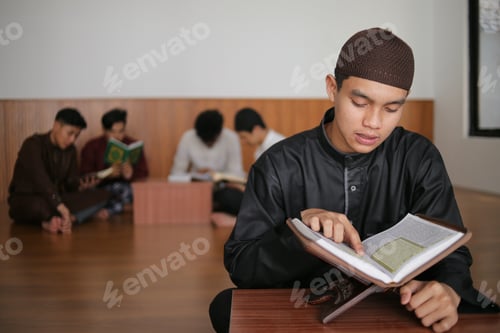Preview: Young Muslim Boy Reading Qur'an At The Mosque Against Muslim Friends Background