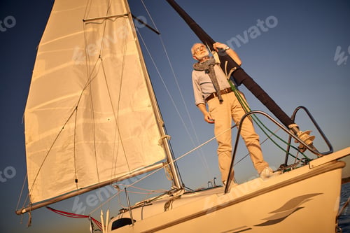 Preview: Senior sailing man standing on the side of a sailboat or yacht deck floating in
