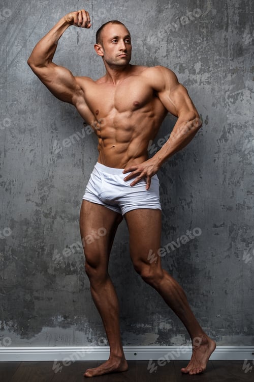 Preview: Sexy and muscular man posing against concrete wall