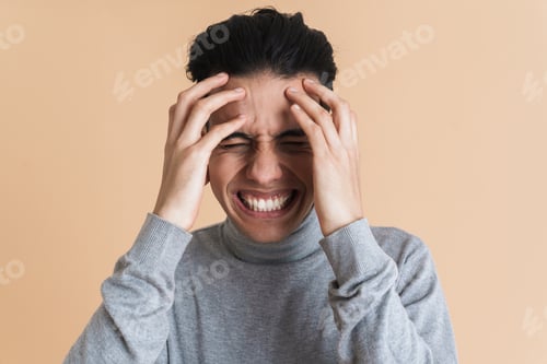 Preview: Young middle eastern man grimacing while holding his head