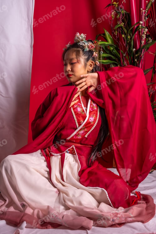Preview: A woman in a red and white dress is sitting on a white surface