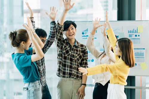 Preview: Happy successful asian business team giving a high fives gesture as they laugh and cheer their suc
