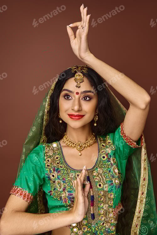 Preview: vertical shot of pretty joyful indian woman with veil and bindi gesturing actively and looking away