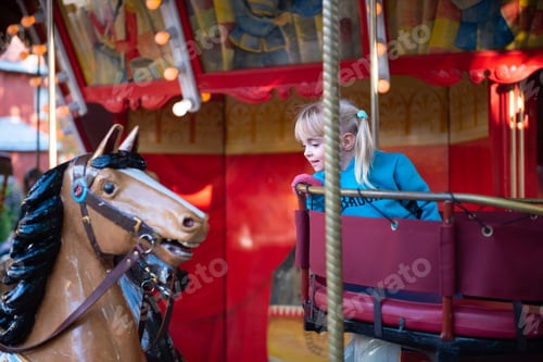 Preview: Cute little girl on the Merry-go-round carousel in the amusement park.